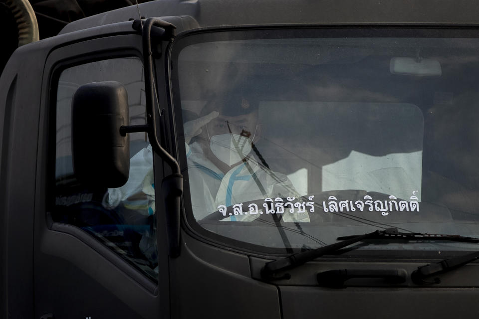A security officer in personal protective clothing salutes as he drives a truck with migrant workers to a field hospital for COVID-19 patents in Samut Sakhon, South of Bangkok, Thailand, Monday, Jan. 4, 2021. For much of 2020, Thailand had the coronavirus under control. After a strict nationwide lockdown in April and May, the number of new local infections dropped to zero, where they remained for the next six months. However, a new outbreak discovered in mid-December threatens to put Thailand back where it was in the toughest days of early 2020. (AP Photo/Gemunu Amarasinghe)
