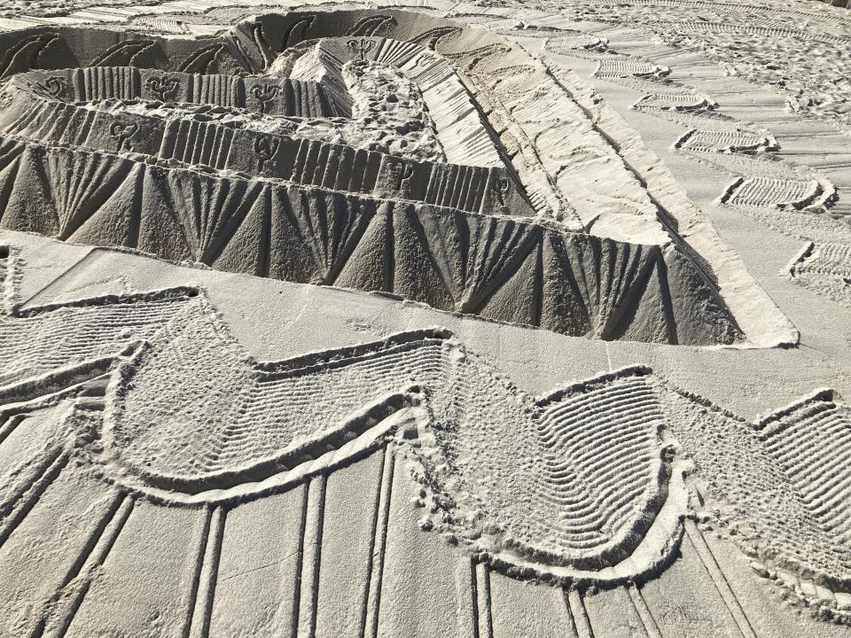 Sand sculptors adorns the beach beside the area that is closed for search and rescue operations at the partially collapsed Champlain Towers South condo building, Friday, July 2, 2021, in Surfside, Fla. (AP Photo/Terry Spencer)