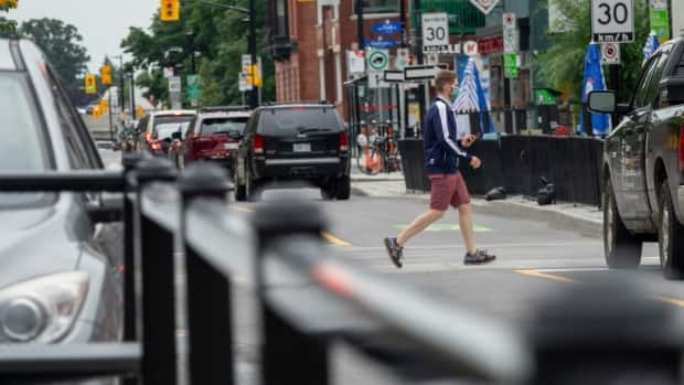 A man in shorts and a face mask crosses the street in Ottawa Thursday. Ottawa reported four new cases of COVID-19 Saturday. (Francis Ferland/CBC - image credit)