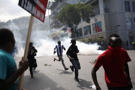 Protesters run away as Haitian National Police officers disperse them with tear gas during a march to demand an investigation into what they say is the alleged misuse of Venezuela-sponsored PetroCaribe funds, in Port-au-Prince, Haiti, October 17, 2018. REUTERS/Andres Martinez Casares