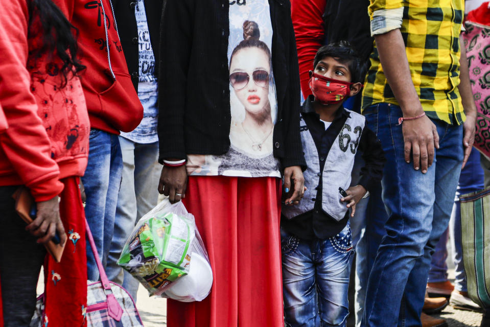 A boy wearing a face mask as a precautionary measure against the coronavirus waits at a crossing with others in Kolkata, India, Saturday, Jan. 2, 2021. (AP Photo/Bikas Das)