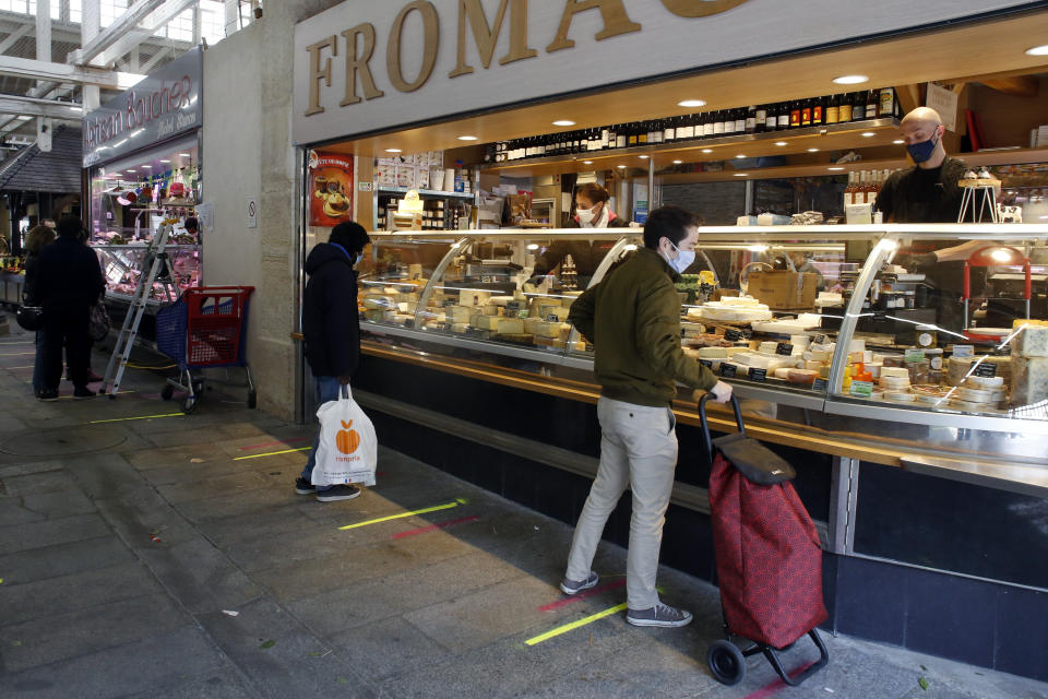 People wearing face mask shop in an indoor food market, in Paris, Tuesday, May 12, 2020.