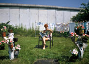 <p>Una mujer lee el periódico en su jardín, que está pegado al muro. (Photo by Thierlein/ullstein bild via Getty Images)</p> 