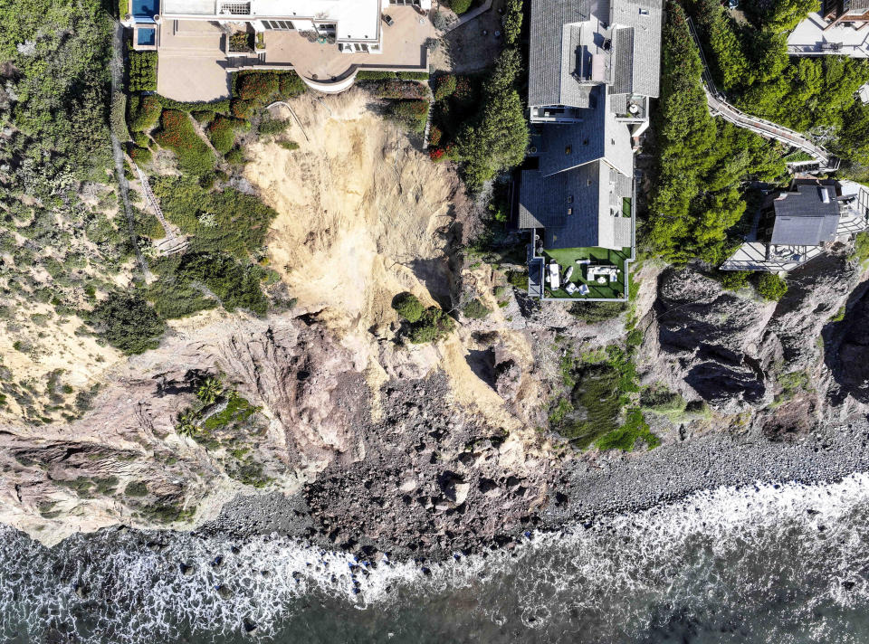 Cliff-top houses along Scenic Drive sit close to a landslide in Dana Point, Calif., on Tuesday, Feb. 13, 2024. The three homes affected by the recent deluge of rain across Orange County are being monitored but don't appear to be in imminent danger, county officials said. (Jeff Gritchen/The Orange County Register via AP)