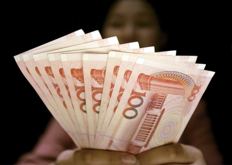 ** FILE ** In this July 22, 2005 file photo, a clerk at an foreign currency exchange desk at a hotel shows Chinese yuan banknotes in Shanghai, China. Beijing's currency has kept climbing Wednesday, June 18, 2008, with the official "parity rate" set at an all-time high against the U.S. dollar as U.S. and Chinese officials resumed talks centering on trade and other strategic issues. (AP Photo/Eugene Hoshiko, File)