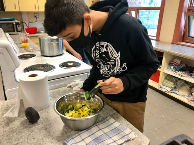 Youdin Ledwell-Cox, a Grade 8 student at Summerside Intermediate, stirs succotash, a dish traditionally eaten by Mi'kmaq.  (Sarah Keaveny Vos/CBC - image credit)