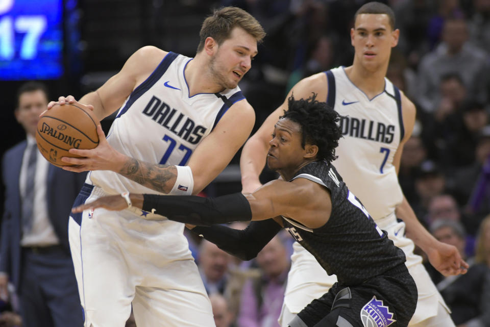 Luka Doncic (77) de los Mavericks de Dallas ante la marca de De'Aaron Fox (5) de los Kings de Sacramento De'Aaron Fox (5) durante el partido dela NBA en Sacramento, California, el miércoles 15 de enero de 2020. (AP Foto/Randall Benton)