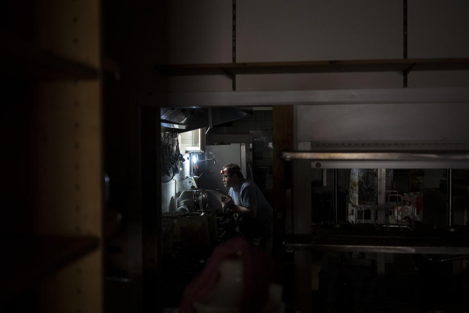 A chef cleans his kitchen of a restaurant hit by the floods in Bad Neuenahr-Ahrweiler, Germany, Monday July 19, 2021. More than 180 people died when heavy rainfall turned tiny streams into raging torrents across parts of western Germany and Belgium, and officials put the death toll in Ahrweiler county alone at 110. (AP Photo/Bram Janssen)