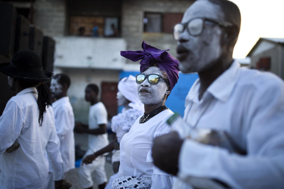 In this Nov. 1, 2018 photo, voodoo believers thought to be possessed with Gede's spirit walk in the middle of the street during the annual Voodoo festival Fete Gede at Cite Soleil Cemetery in Port-au-Prince, Haiti. During the festival, believers dress up as Gede spirits known as "Loas" and say they become possessed by those who hear their prayers and provide favors to members of their congregation. (AP Photo/Dieu Nalio Chery)