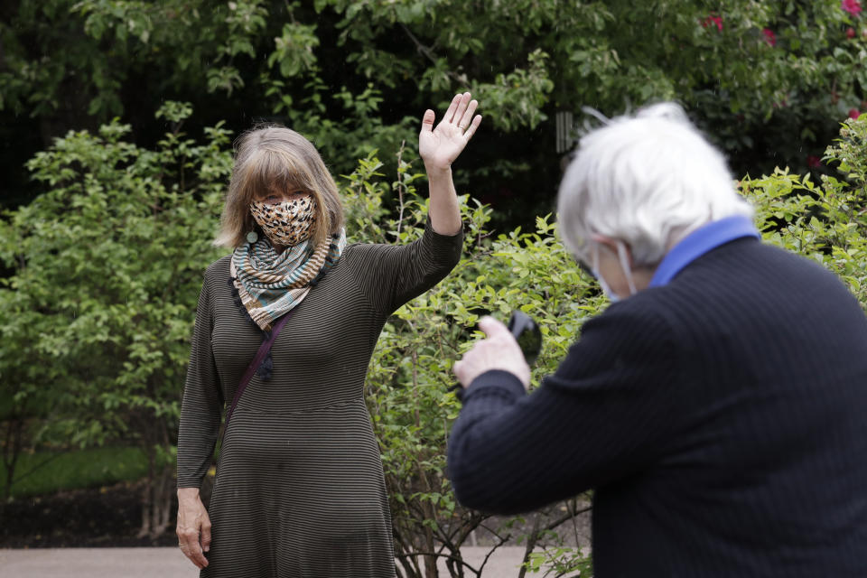 The Rev. Jane Pauw, left, waves goodbye to her friend, Jessie Cornwell, a resident of the Ida Culver House Ravenna, after they were photographed in Seattle on May 21, 2020. Cornwell tested positive for the coronavirus but never became ill, and may have been infectious when she shared a ride to Bible study with Pauw, who later got sick with COVID-19. (AP Photo/Elaine Thompson)