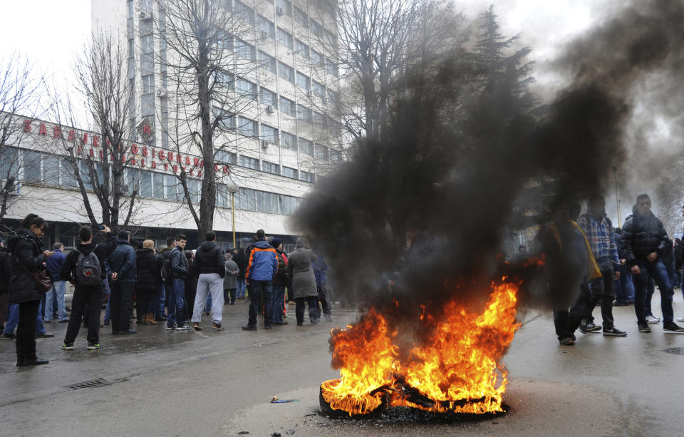 A tyre burns in the street as protesters stoned a local government building in the Bosnian town of Tuzla, 140 kms north of Sarajevo, Thursday, Feb. 6, 2014. Several hundred protesters clashed with police as they tried to storm into the building of the local government and confront the officials there whom they blame for allowing the city's major state-owned companies to go bankrupt after dubious privatizations. The four former state-owned companies that employed most of Tuzla's population were sold but the contracts obliged the new owners to invest in them and make them profitable. But those just sold the assets, stopped paying workers, and filed for bankruptcy. The authorities did nothing about such violation of sales contracts.(AP Photo/Darko Zabus)
