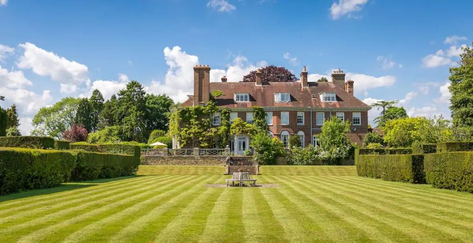 a large house with a lawn and hedges in front of it