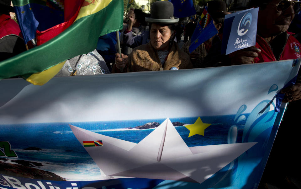 A woman holds a Bolivian national flag as she waits for the live broadcast of a ruling from the United Nations' highest court, in La Paz, Bolivia, Monday, Oct. 1, 2018. In a legal ruling from the Hague-based International Court of Justice, the court rejected a request by Bolivia for its judges to order Chile to negotiate a way of granting landlocked Bolivia access to the Pacific Ocean. (AP Photo/Juan Karita)