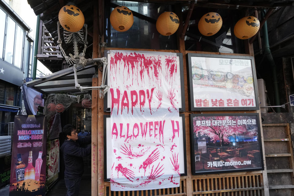 A government official attaches a notice announcing the closure for victims near the scene of a deadly accident in Seoul, South Korea, Sunday, Oct. 30, 2022, following Saturday night's Halloween festivities. A mass of mostly young people celebrating Halloween festivities in Seoul became trapped and crushed as the crowd surged into a narrow alley, killing dozens of people and injuring dozens of others in South Korea's worst disaster in years. (AP Photo/Ahn Young-joon)