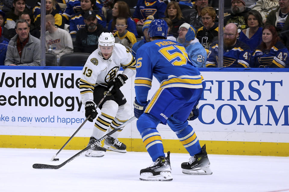 Boston Bruins' Charlie Coyle (13) controls the puck as St. Louis Blues' Colton Parayko (55) defends during the third period of an NHL hockey game Saturday, Jan. 13, 2023, in St. Louis. (AP Photo/Scott Kane)