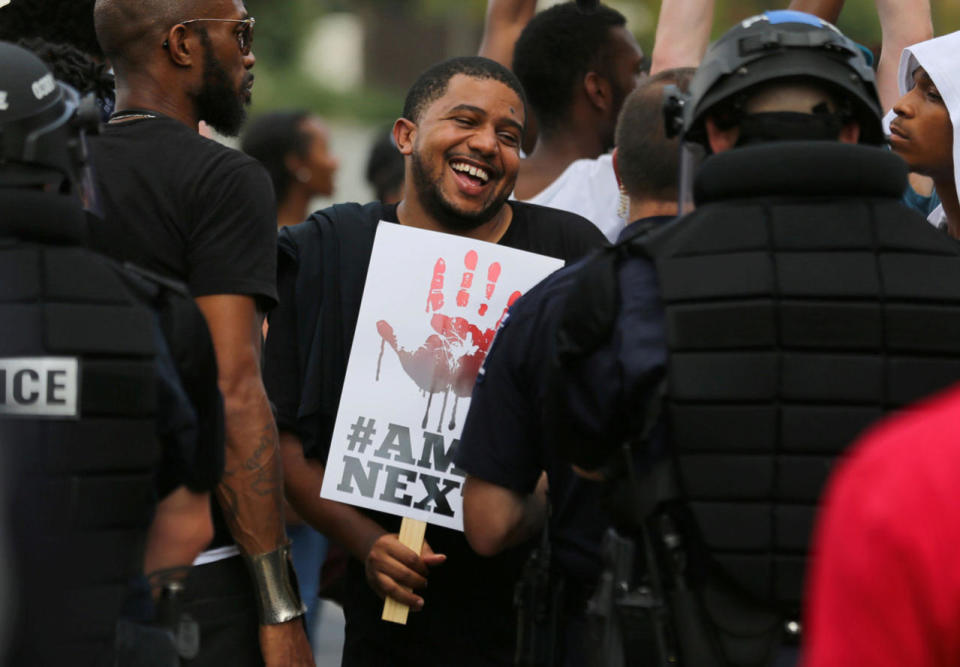 <p>A demonstrator shares a laugh with a police officer in riot gear as people protest the police shooting of Keith Scott, outside the football stadium where the NFL’s Carolina Panthers are hosting the Minnesota Vikings in Charlotte, N.C., on Sept. 25, 2016. (Mike Blake/Reuters)</p>