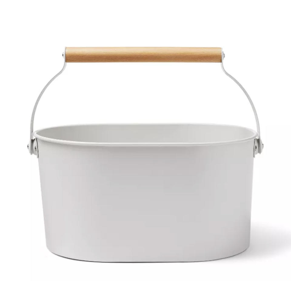 A grey cleaning caddy with a metal and wooden handle