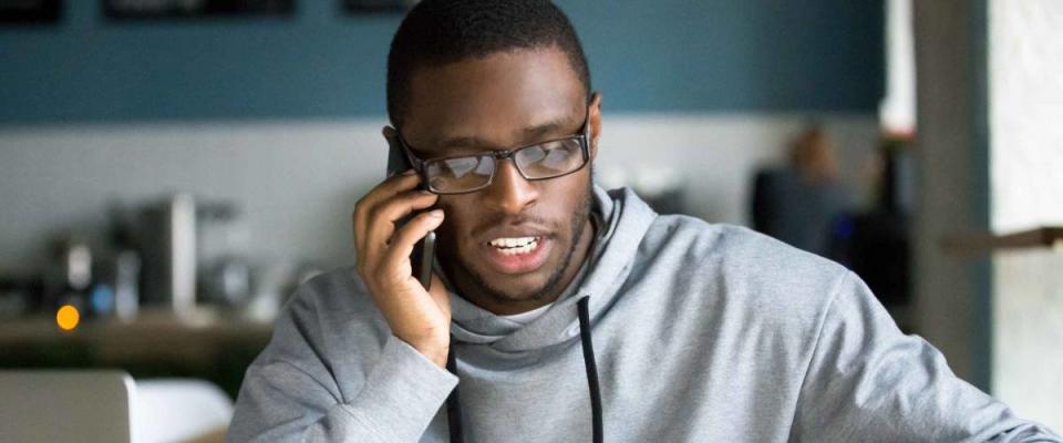 Man talking on phone sitting at cafe table