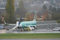 Workers stand near a Boeing 737 Max airplane parked at Renton Municipal Airport, Wednesday, Nov. 18, 2020, next to the Boeing assembly facility in Renton, Wash. where 737 Max airplanes are made. After nearly two years and a pair of deadly crashes, the U.S. Federal Aviation Administration announced Wednesday that the 737 Max has been cleared for flight after regulators around the world grounded the Max in March 2019, after the crash of an Ethiopian Airlines jet. (AP Photo/Ted S. Warren)