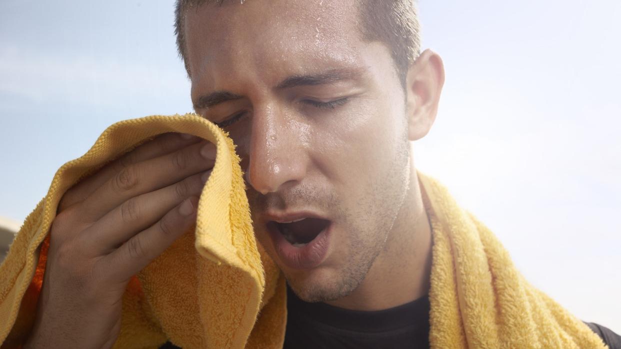 A sweating young man with a yellow towel.