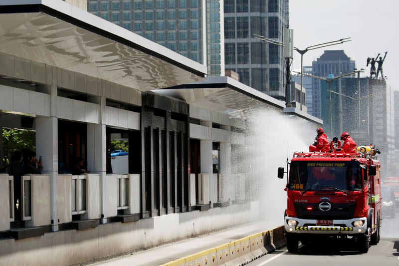 Firefighters spray disinfectant on a public bus station using high pressure pump truck to prevent the spread of the coronavirus disease (COVID-19), on the main road in Jakarta