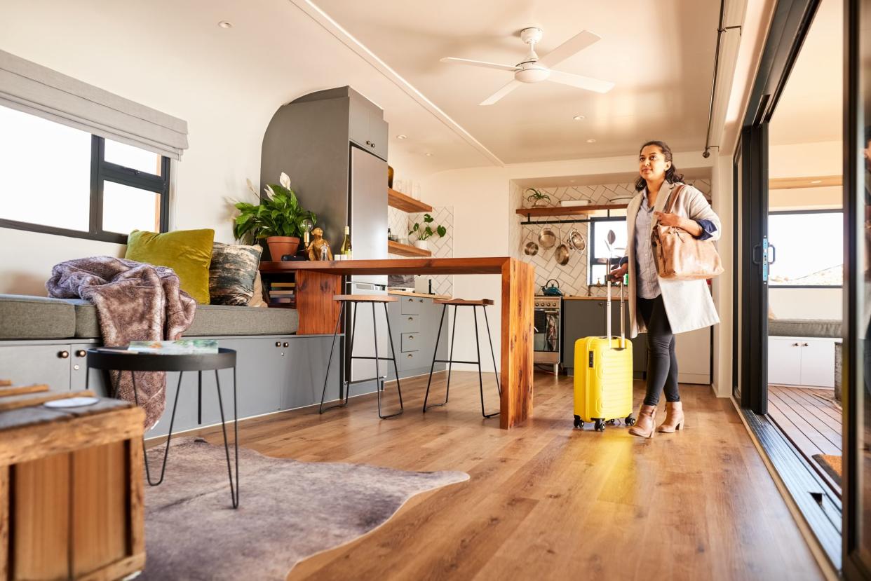 Young woman with a suitcase looking around while standing at vacation rental home