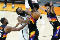 Brooklyn Nets guard James Harden dishes around Phoenix Suns center Deandre Ayton, right, during the first half of an NBA basketball game, Tuesday, Feb. 16, 2021, in Phoenix.(AP Photo/Matt York)