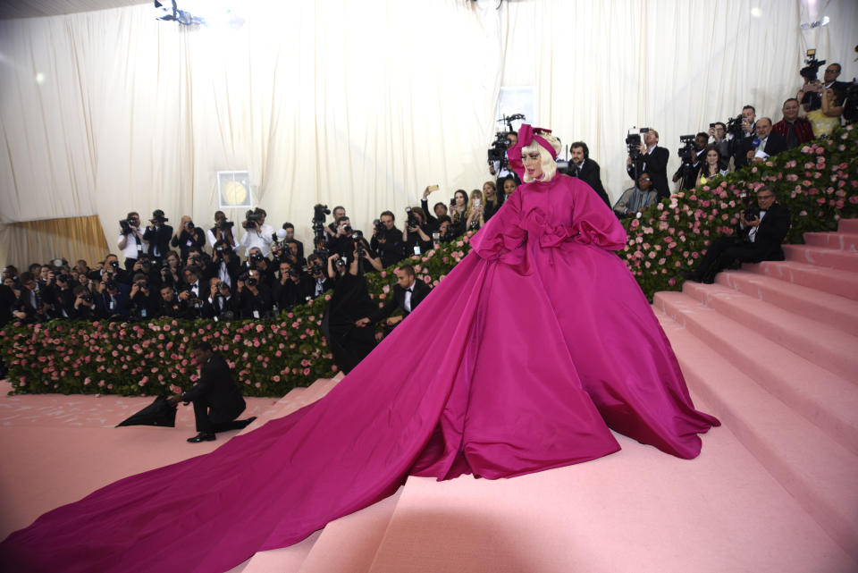 Lady Gaga in voluminous pink gown with bow accents at a Met Gala event, posing on stairs