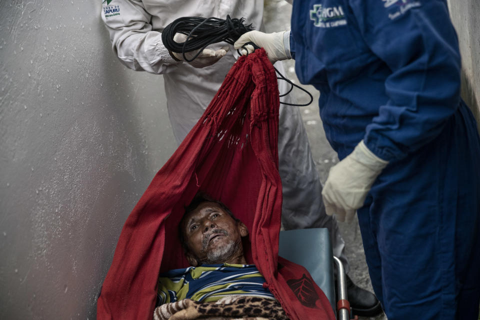 Con su hamaca como camilla, trabajadores de urgencias recogen en su casa de Manacapuru, estado de Amazonas, Brasil, a José de Almeida Rocha, quien presentaba síntomas de COVID, el 1 de junio de 2020. (Tyler Hicks/The New York Times).