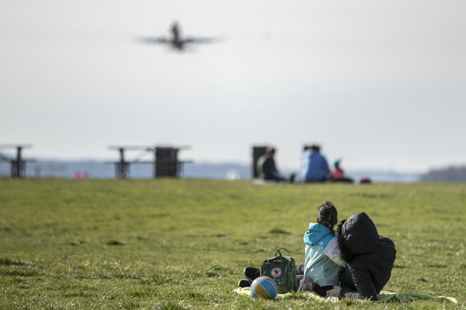 Visitors to Gravelly Point watch as a plane takes off from Ronald Reagan Washington National Airport, Monday, March 16, 2020, in Arlington, Va. (AP Photo/Andrew Harnik)