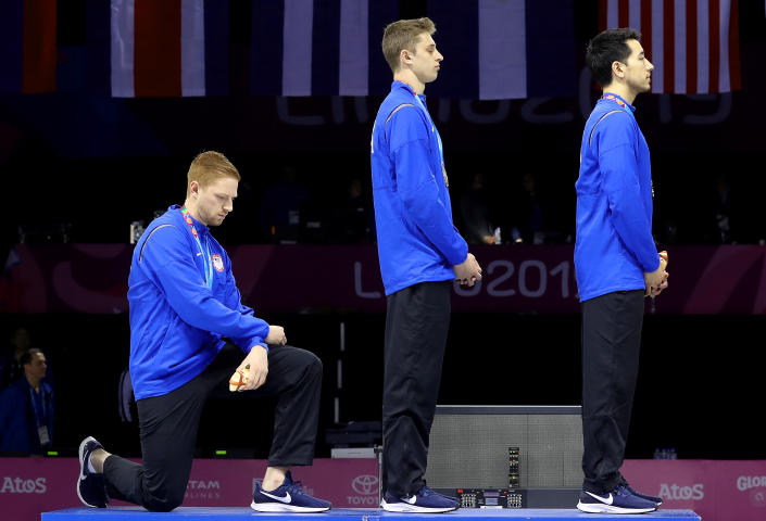 LIMA, PERU - AUGUST 09: Gold medalist Race Imboden of United States takes a knee during the National Anthem Ceremony in the podium of Fencing Men's Foil Team Gold Medal Match Match on Day 14 of Lima 2019 Pan American Games at Fencing Pavilion of Lima Convention Center on August 09, 2019 in Lima, Peru. (Photo by Leonardo Fernandez/Getty Images)