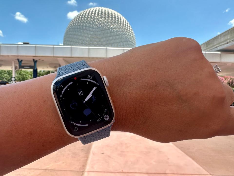 terri holding up her apple watch on her wrist in front of the epcot ball at disney world