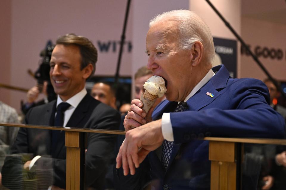 President Joe Biden (right), flanked by host Seth Meyers (left), eats an ice cream cone at Van Leeuwen Ice Cream after taping an episode of "Late Night with Seth Meyers" in New York City on February 26, 2024.