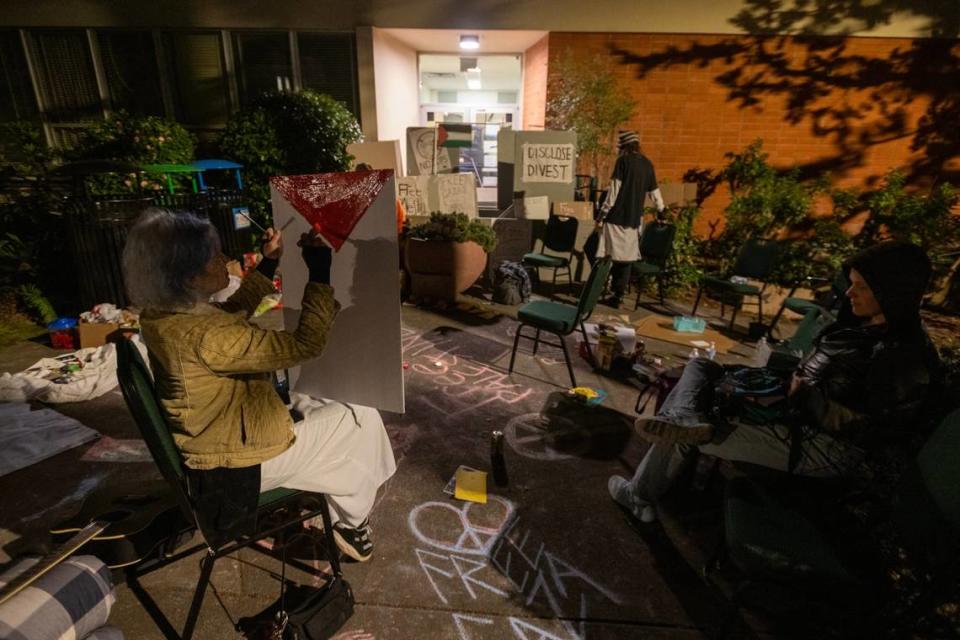 Cal Poly Humboldt student Tabs Born paints a Palestine Flag on Tuesday, April 23, 2024, outside barricaded Siemens Hall, which students and community members have occupied to call for a permanent ceasefire in Gaza.