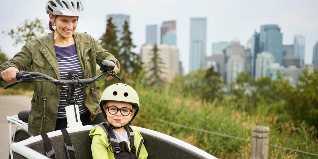 smiling mom and riding a cargo bike with her young son