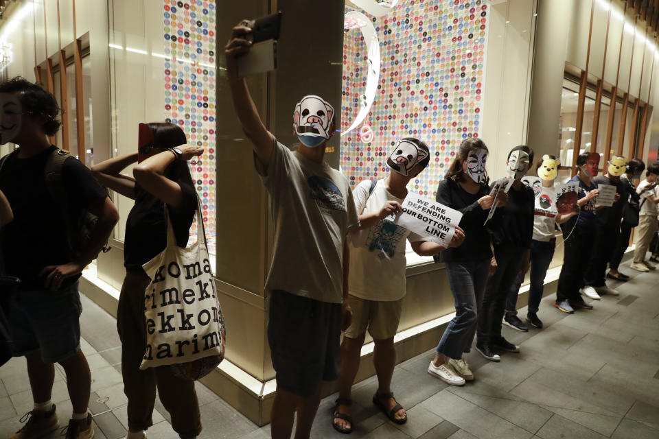 Protesters takes selfies while wearing masks during a protest in Hong Kong, Friday, Oct. 18, 2019. Hong Kong pro-democracy protesters are donning cartoon/superhero masks as they formed a human chain across the semiautonomous Chinese city, in defiance of a government ban on face coverings. (AP Photo/Mark Schiefelbein)