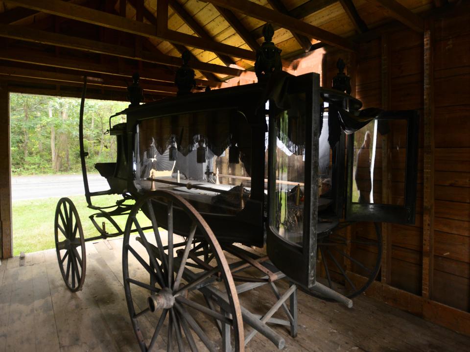 David Martin, president of the Marstons Mills Historical Society reflects up in the window of the town's old horse drawn hearse housed in a small shed dating to 1880 at the Marstons Mills Cemetery off Route 149 in that town.