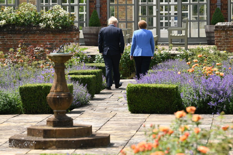 Britain's Prime Minister Boris Johnson, left, and German Chancellor Angela Merkel, walk through the garden at Chequers, the country house of the Prime Minister, in Buckinghamshire, England, Friday July 2, 2021. Johnson is likely to push Angela Merkel to drop her efforts to impose COVID-19 restrictions on British travelers as the German chancellor makes her final visit to Britain before stepping down in the coming months. Johnson will hold talks with Merkel at his country residence on Friday. (Stefan Rousseau/Pool Photo via AP)