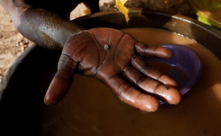 An informal gold miner holds a nugget of gold after it was gathered using mercury at the site of Nsuaem-Top