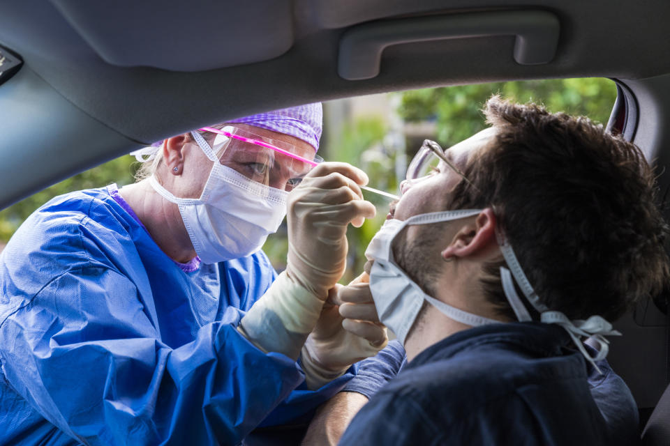 A doctor in a protective suit taking a nasal swab from a person to test for possible coronavirus infection