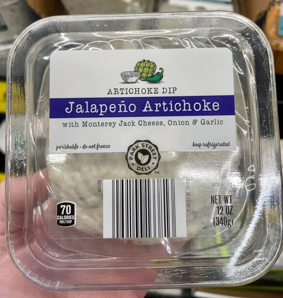 Hand holding clear package of Aldi jalepeno artichoke dip