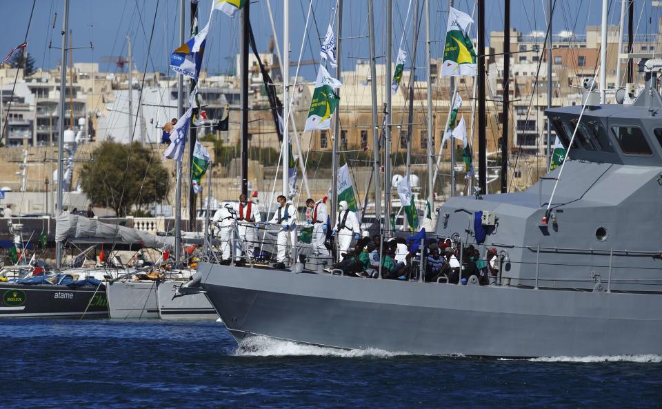 An AFM patrol boat carrying rescued migrants passes yachts as it approaches the AFM Maritime Squadron base at Haywharf in Valletta's Marsamxett Harbour