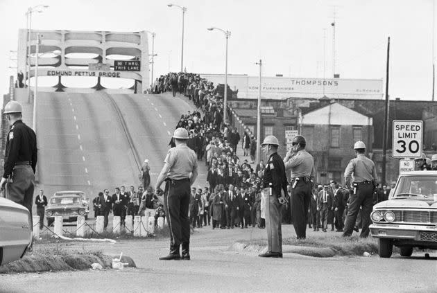 State troopers watch as civil rights marchers cross the Edmund Pettus Bridge over the Alabama River in Selma, Alabama two days before troopers used excessive force driving marchers back across the bridge, killing one protester. (Photo: Bettmann via Getty Images)