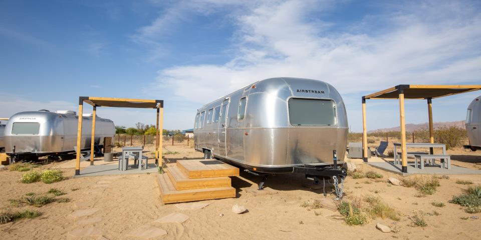 Airstream trailers outside at Autocamp's Joshua Tree location. There's tables and chairs between each trailer.