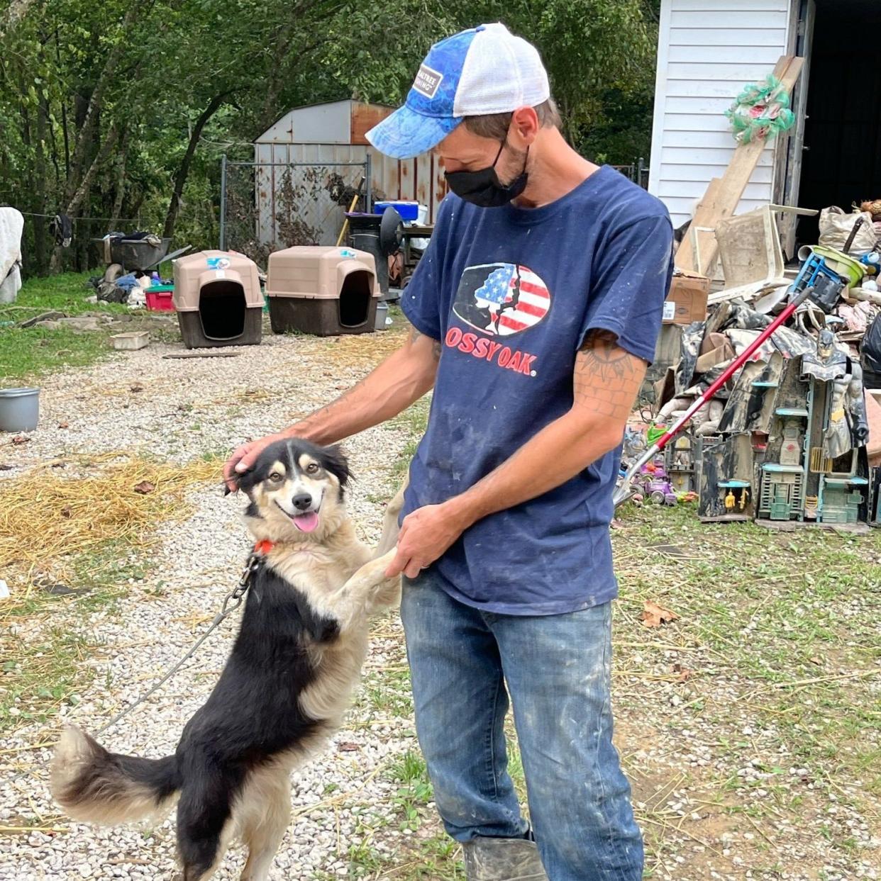 Kentucky resident Greg Stivers plays with one of his dogs outside of his flood-damaged home. American Humane helped Stivers and his family care for their pets in the aftermath of catastrophic floods that affected eastern Kentucky last month.