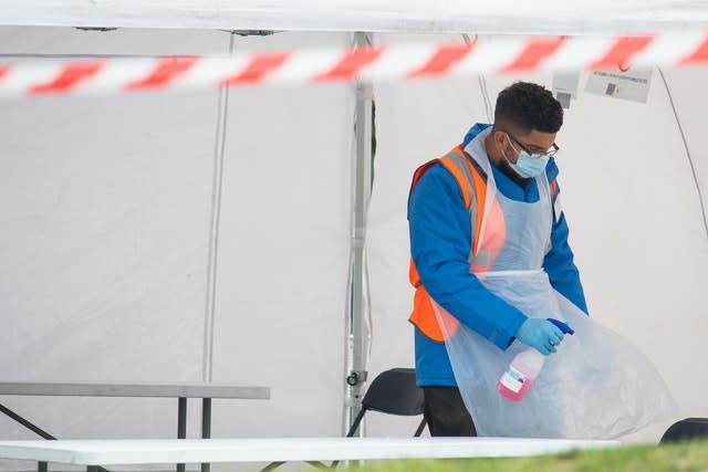 A member of staff disinfects tables between tests at a walk in Covid-19 testing centre in Southwark, south London (Dominic Lipinski/PA)