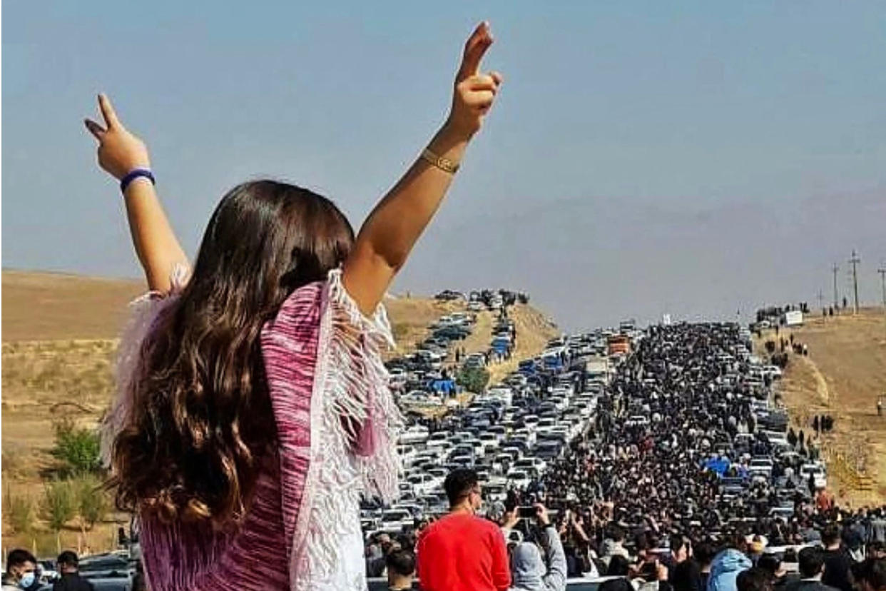 An unveiled woman stands on top of a vehicle as thousands make their way towards Aichi cemetery in Saqaez, Mahsa Amini's hometown in Iranian Kurdistan, to mark 40 days since her death, on Oct. 26, 2022. (via Twitter / AFP - Getty Images)