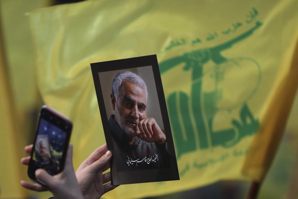 A Hezbollah supporter uses her mobile phone to takes a picture of photo of slain Iranian Revolutionary Guard Gen. Qassem Soleimani during a ceremony marking the anniversary of the assassination of Hezbollah leaders, Abbas al-Moussawi, Ragheb Harb and Imad Mughniyeh and the end of a 40-day Muslim mourning period for Soleimani, in the southern suburb of Beirut, Lebanon, Sunday, Feb. 16, 2020. Nasrallah said U.S. President Donald Trump declared war on the Middle East when the U.S. assassinated Soleimani and when the White House announced its plan to end the Palestinian-Israeli conflict. He called on all to resist U.S. influence and its troops presence. (AP Photo/Hassan Ammar)