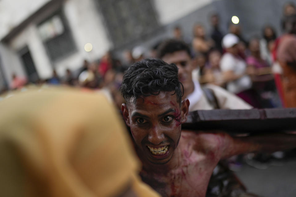 Un penitente que interpreta a uno de los dos ladrones condenados a la crucifixión junto a Jesús, carga con su cruz durante una representación del Via Crucis, como parte de la celebración de la Semana Santa, en el vecindario de Petare de Caracas, Venezuela, el 29 de marzo de 2024. La Semana Santa conmemora los últimos días de la vida de Jesús, según la Biblia, incluyendo su crucifixión el Viernes Santo y su resurrección en el Domingo de Pascua. (AP Foto/Matías Delacroix)