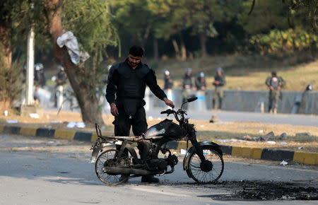 A policeman retrieves his motorcycle which was burned during clashes with protesters near the Faizabad junction in Islamabad, Pakistan November 26, 2017. REUTERS/Caren Firouz